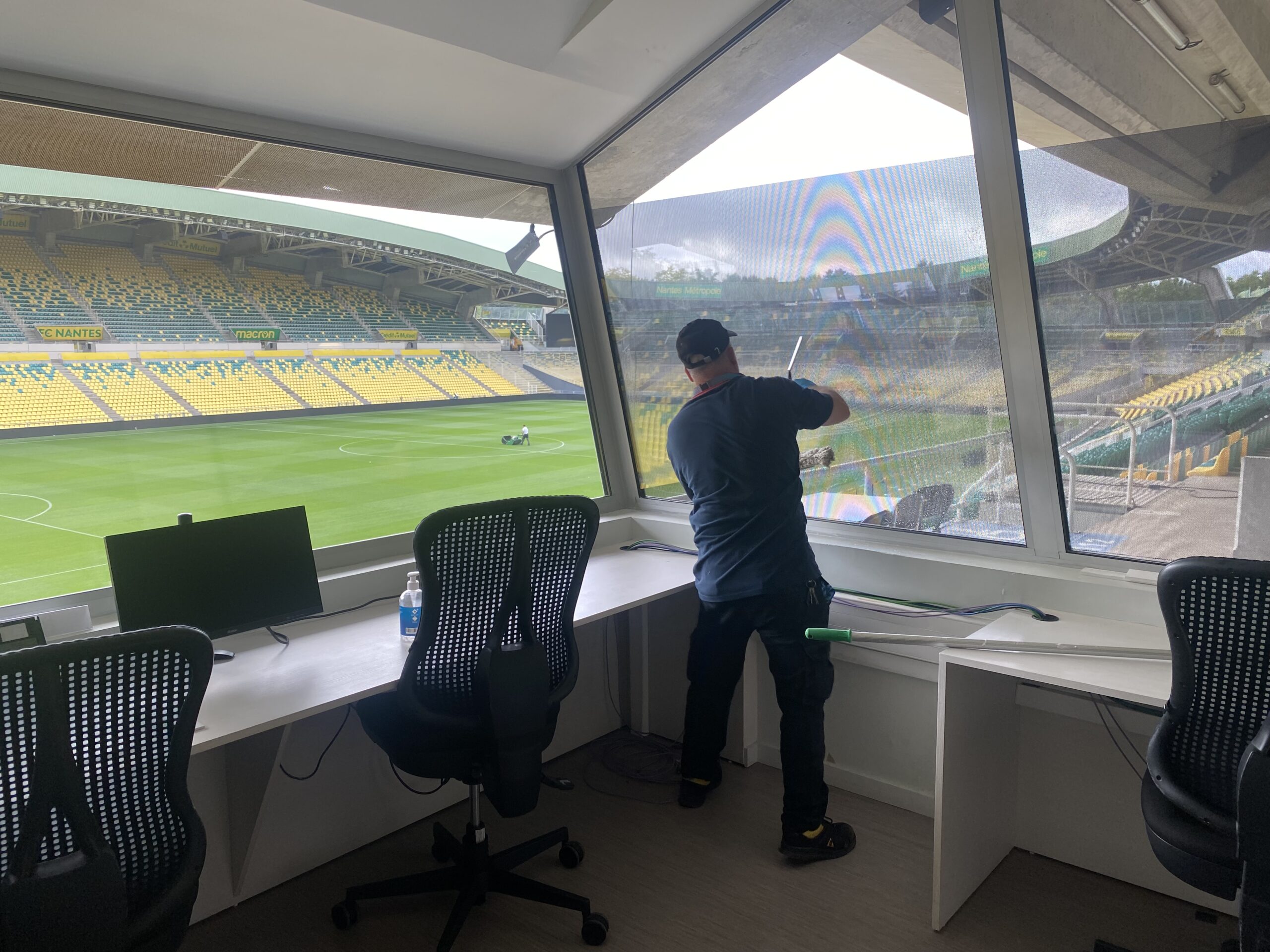 Agent de Service de chez ISOR Group, nettoyant une vitre au stade de la Beaujoire.